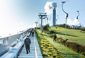 Skiing people on a pitched green roof and stairs up to the top