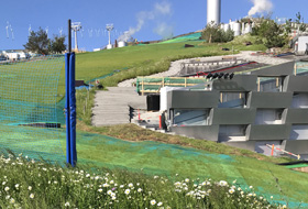 Grass growing through the synthetic mats on the skiing slope on a green roof